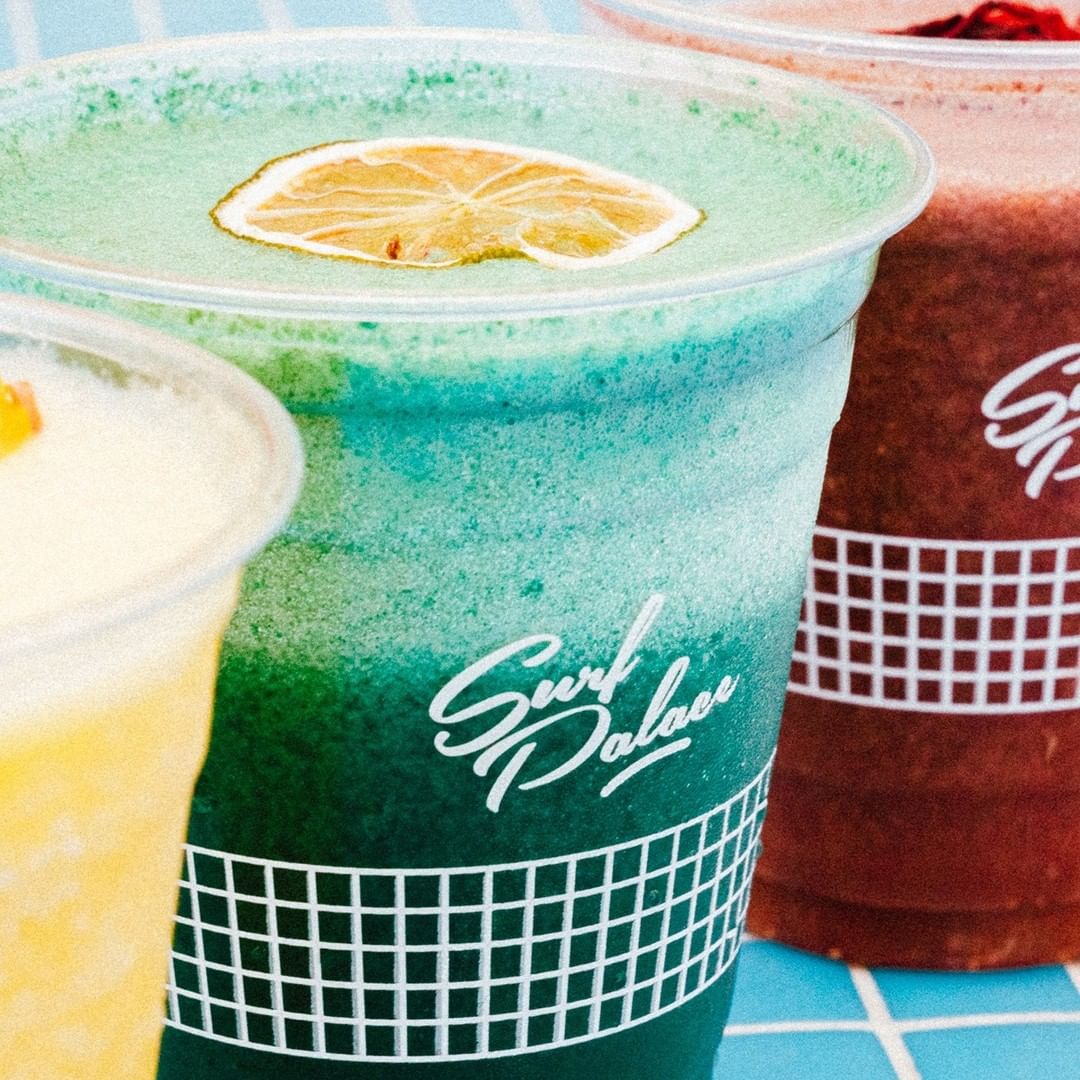 Refreshing tropical smoothies in personalised smoothie cups with Surf Palace branding, showcasing vibrant colors and garnished with dried citrus slices for a beachy vibe.